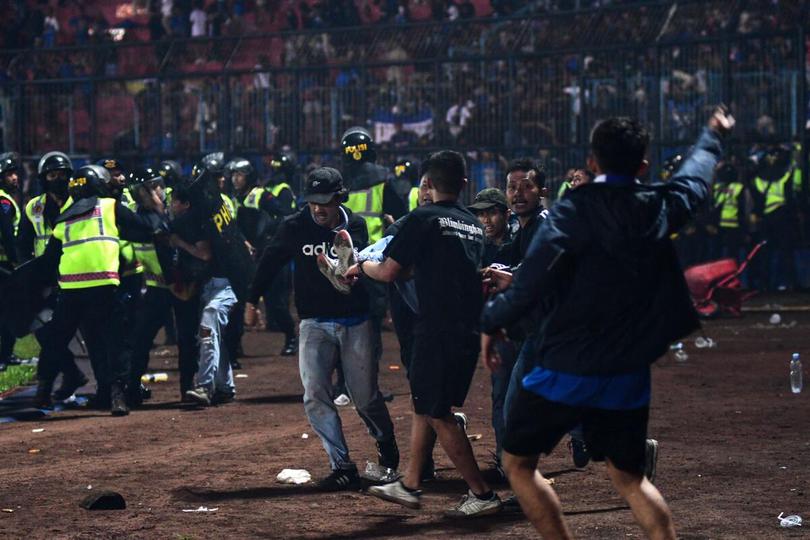 A group of people carry a man at the stadium during the violence. | Photo Credit: AFP