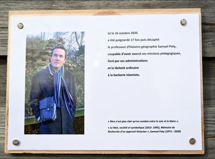 A photograph taken on October 16, 2023 shows a commemorative plaque for slain teacher Samuel Paty (portrait) near the Bois d'Aulne school in Conflans-Sainte-Honorine, outside Paris. Photo Credit: AFP